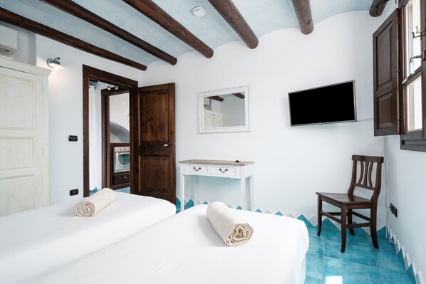 A hotel room with two beds, a desk, a chair, a TV, and a mirror.