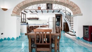 Una cocina con comedor, un arco de ladrillo y un horno de leña rojo.