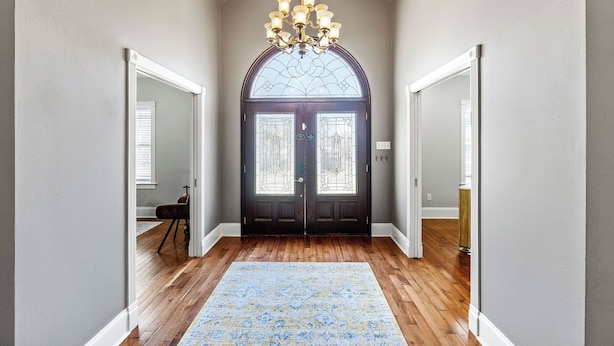 A hallway with a wooden floor, a large rug, a chandelier, and a double door with glass panels. - Downtown Estate Property close to Southeastern (Hammond)
