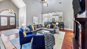 A spacious living room with a sectional sofa, a fireplace, and a dining area with a kitchen in the background. - Downtown Estate Property close to Southeastern (Hammond)