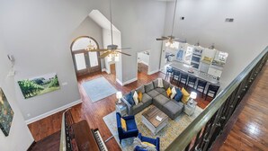 A spacious living area with a large sectional sofa, a piano, and a dining area with a kitchen in the background. - Downtown Estate Property close to Southeastern (Hammond)