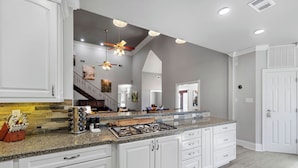 A modern kitchen with white cabinetry, granite countertops, and a central island. - Downtown Estate Property close to Southeastern (Hammond)