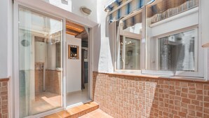 A narrow outdoor corridor with a glass door leading to a room, a tiled wall, and a window with a curtain. - Holiday Apartment 'Planta Baja' (Íllora)