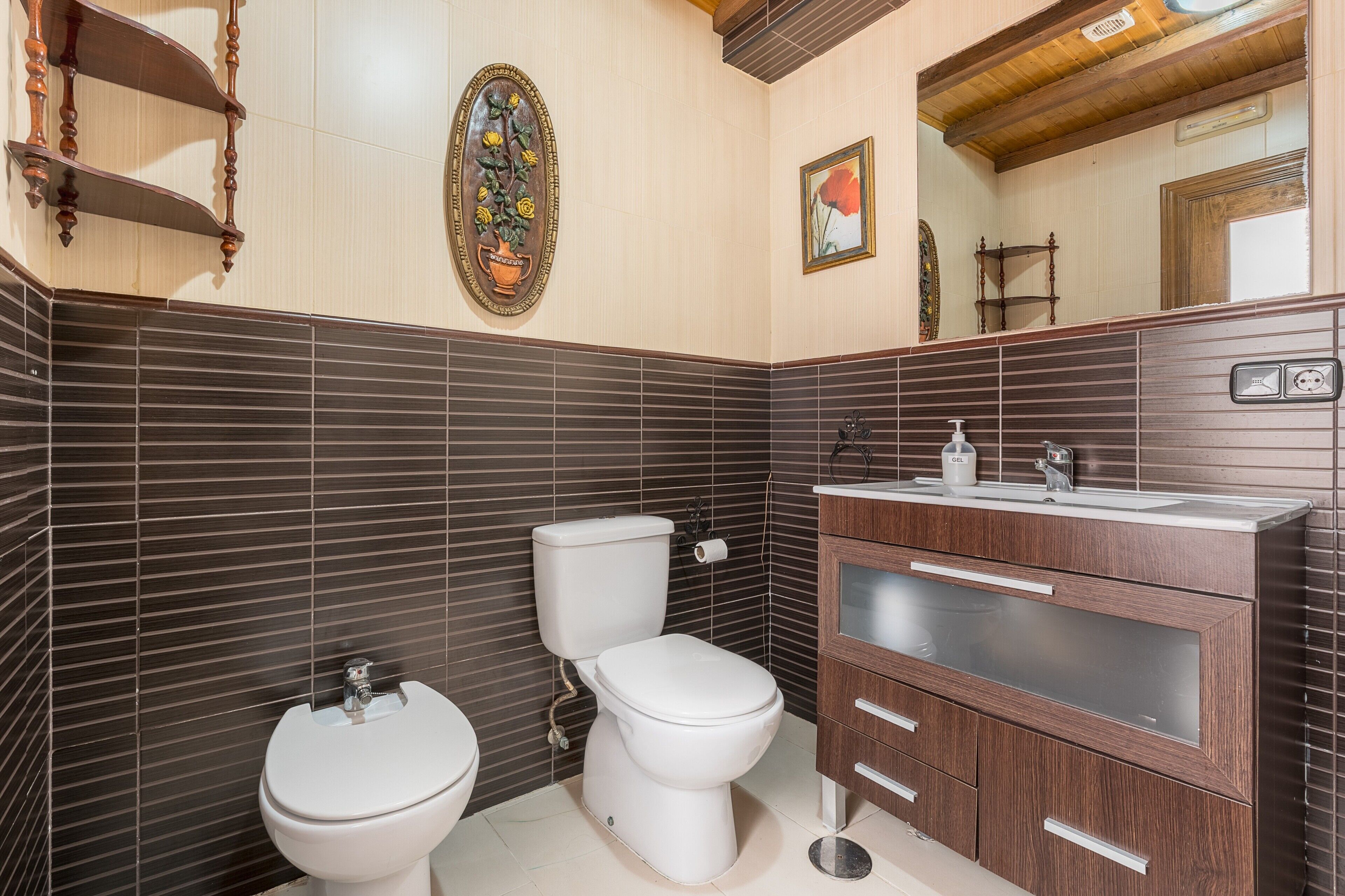Un baño con inodoro, bidé y tocador de madera con espejo.