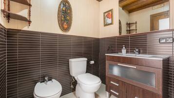 Un baño con inodoro, bidé y tocador de madera con espejo.