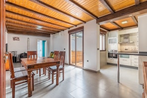 Un grand espace à manger, doté de meubles en bois et offrant une vue sur un balcon.