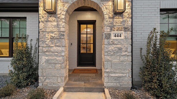 A stone facade with a black door and two wall-mounted lights. - Charming new home in downtown New Braunfels, close to shops, dining & more! (New Braunfels)