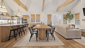 A spacious kitchen with a central island, wooden beams, and a large dining table surrounded by chairs. - Charming new home in downtown New Braunfels, close to shops, dining & more! (New Braunfels)