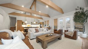 A spacious living room with a large wooden coffee table, a sofa set, and a dining area in the background. - Charming new home in downtown New Braunfels, close to shops, dining & more! (New Braunfels)