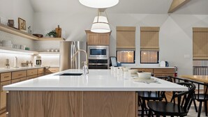 A modern kitchen with a central island, wooden cabinets, and built-in appliances. - Charming new home in downtown New Braunfels, close to shops, dining & more! (New Braunfels)