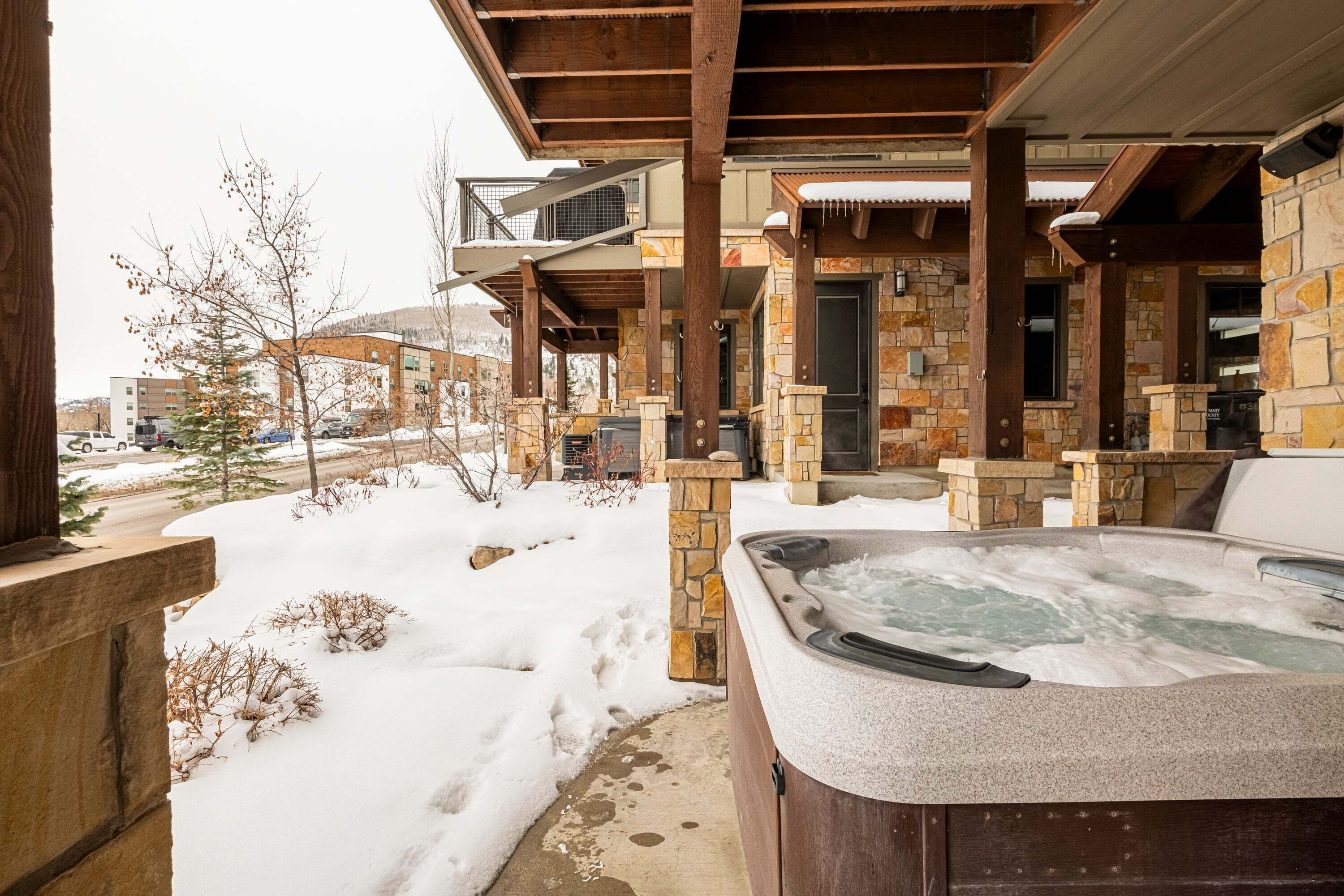 Un bain à remous à l’extérieur d’un bâtiment en pierre, avec une terrasse couverte.