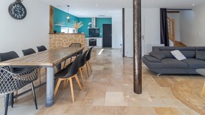 A modern living space with a dining area, kitchen, and a staircase. - Le Séchoir – Authentic House with Private Pool in Périgord Noir, Perfect for Families or Groups (Coly-Saint-Amand)