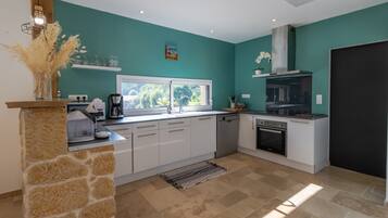 A modern kitchen with white cabinets, a stone accent wall, a built-in oven, and a window providing natural light.