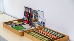 A wooden tray with magazines and a wooden box with rolled-up items.