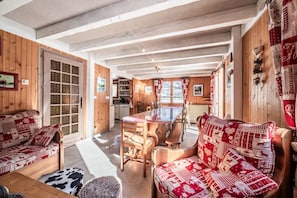 Un acogedor interior de cabaña con paredes de madera, una mesa de comedor y un sofá con cojines estampados.