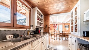 A kitchen with wooden cabinets, a sink, and a view of the outside. - Chalet 'Phidel - 11 People' with Mountain Views, Private Terrace, and Wi-Fi (Bernex)