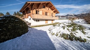 A wooden chalet with a balcony, surrounded by snow-covered ground and mountains in the background. - Chalet 'Phidel - 11 People' with Mountain Views, Private Terrace, and Wi-Fi (Bernex)