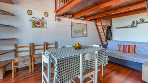 Ein gemütliches Zimmer mit Schlafkoje, Esstisch mit Stühlen, einer Couch und einer Treppe.