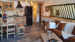 Une cuisine moderne avec des meubles en bois, un réfrigérateur noir et un coin repas comprenant des chaises et une table en bois.