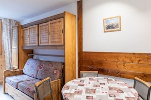 A cozy room with a wooden sofa, a round table, and a wall-mounted picture.