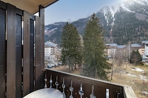 A balcony with a view of a mountainous landscape, buildings, and trees.