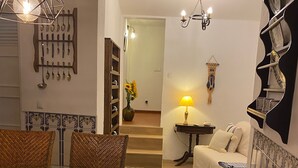 Un salon comprenant un coin repas, un canapé, une lampe et une étagère fixée au mur.