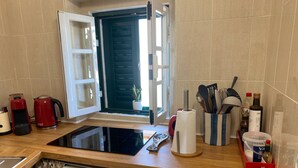 Une cuisine équipée d’un lave-vaisselle, d’une machine à café, d’une bouilloire, d’un porte-essuie-tout et d’une fenêtre avec vue.