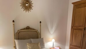 Un lit bien fait, agrémenté d’une tête de lit décorative, d’une lampe de chevet et d’une armoire en bois.