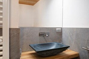 A bathroom with a stone sink, wooden countertop, and a modern faucet.