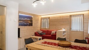 Un interior de madera con una mesa de comedor, un sofá rojo y un cuadro colgado.