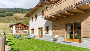A modern chalet with a spacious patio, wooden balconies, and a view of the surrounding hills. - Studio 'Pino Mugo' with Mountain View, Balcony and Wi-Fi (Livigno)