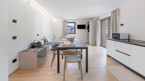 A modern kitchen with a dining area, a flat-screen TV, and a view of the outdoors. - Studio 'Pino Mugo' with Mountain View, Balcony and Wi-Fi (Livigno)