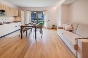 Eine moderne Küche mit Holdekor, einem Esstisch mit Stühlen, einer Couch und einem kleinen Beistelltisch mit Pflanze.