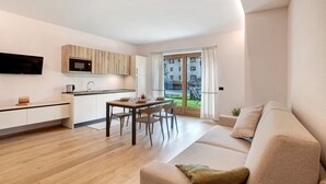 A modern apartment with a kitchen, dining area, and a living room with a sofa. - Apartment 'Larice' with Mountain View, Private Garden and Wi-Fi (Livigno)