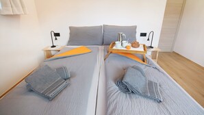 A double bed with grey bedding, a tray with a coffee pot, mug, and a bowl, and a small table with a lamp. - Apartment 'Larice' with Mountain View, Private Garden and Wi-Fi (Livigno)