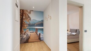 A hallway with a wooden floor leading to a bedroom with a bed and a view of a lake through a mural. - Apartment 'Stella Alpina' with Mountain View, Private Garden and Wi-Fi (Livigno)