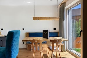 A dining area with a wooden table and chairs, a blue cushioned bench, and a menu stand. - Apartment 'Moarhof  Salbei' with Mountain View, Private Terrace and Wi-Fi (Mölten/Schlaneid)