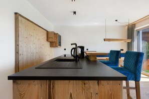 A modern kitchen with a wooden island, black countertop, and a kettle. - Apartment 'Moarhof  Salbei' with Mountain View, Private Terrace and Wi-Fi (Mölten/Schlaneid)