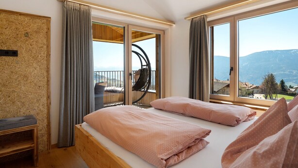 Una habitación con una cama, una silla y vistas a las montañas.