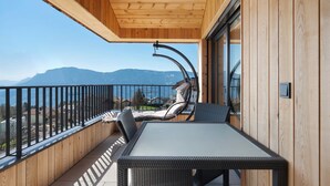 Un balcón con mesa y sillas, techo de madera y vistas a las montañas.