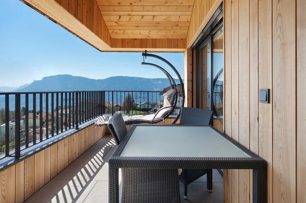 Un balcon avec une table et des chaises, un plafond en bois et une vue sur les montagnes.