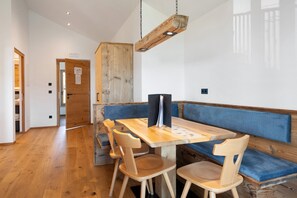Un espace repas avec une table en bois, des bancs rembourrés bleus et un luminaire suspendu.