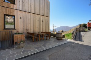 Un bâtiment en bois doté d’un patio en pierre, de meubles en bois et offrant une vue sur les montagnes.