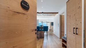 A wooden interior with a kitchen area, bar stools, and a wooden wardrobe.
