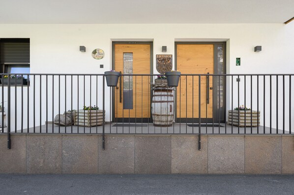 A building with two wooden doors, a metal fence, and planters with flowers.