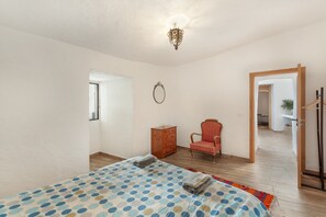 Une chambre à coucher comprenant un lit, une commode, une chaise et un couloir menant à une autre pièce.