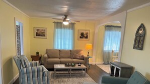 Een woonkamer met een bank, twee fauteuils, een salontafel en een lamp.
