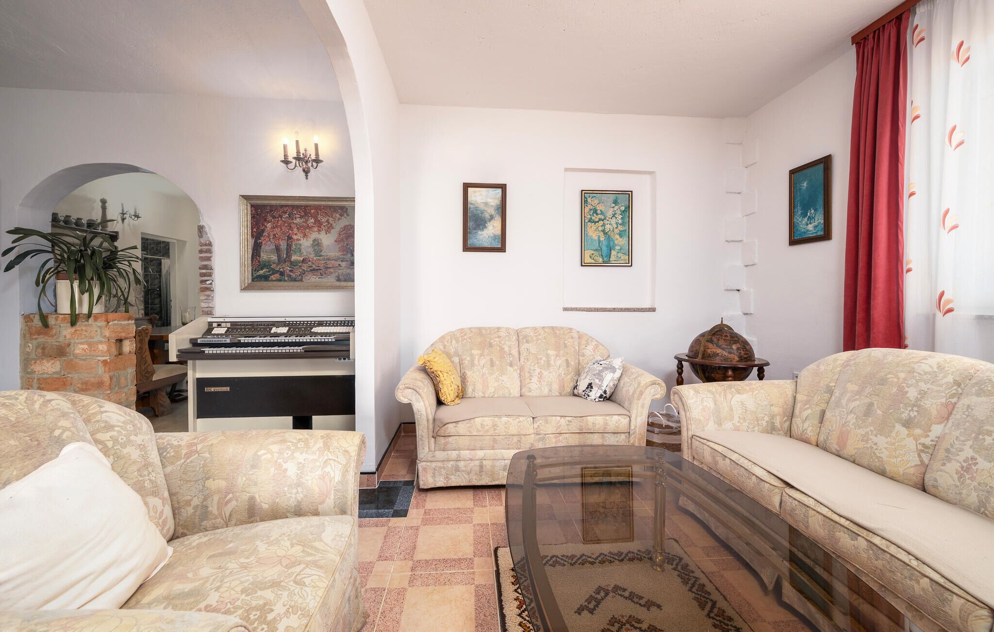 A living room with a piano, two sofas, a glass coffee table, and a brick fireplace.