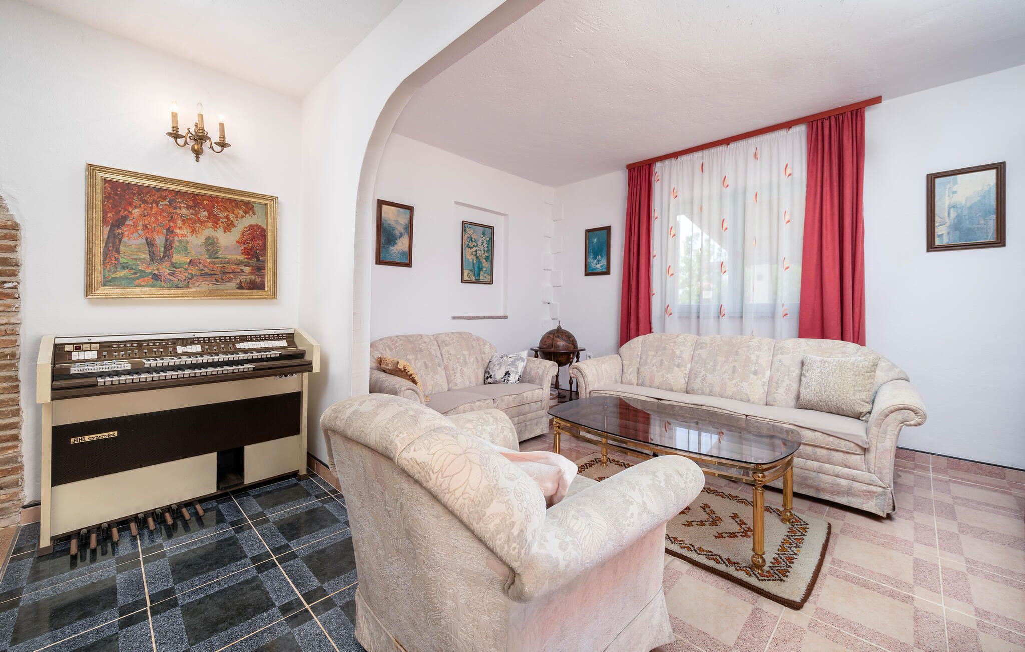 Een woonkamer met een piano, twee banken, een salontafel en een vloerkleed.