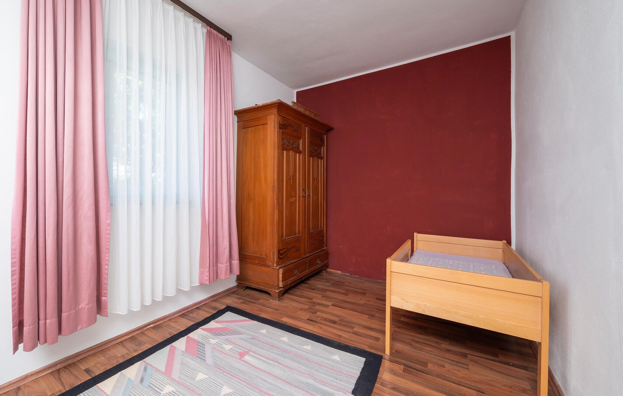 Ein Schlafzimmer mit einem hölzernen Bett, einem Holzschrank und einem gemusterten Teppich.